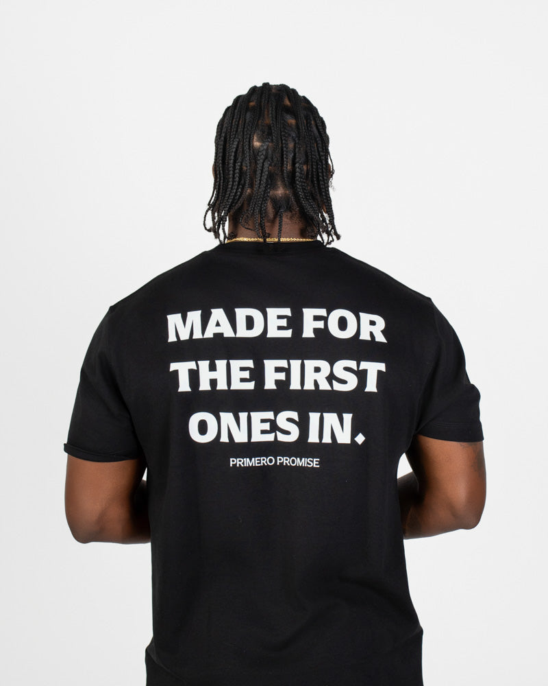 Person wearing a black t-shirt with white text on the back, standing against a plain background.